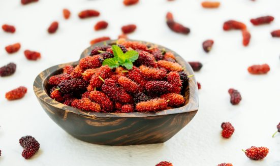 Red and Black mulberry fruit in bowl on white stone background